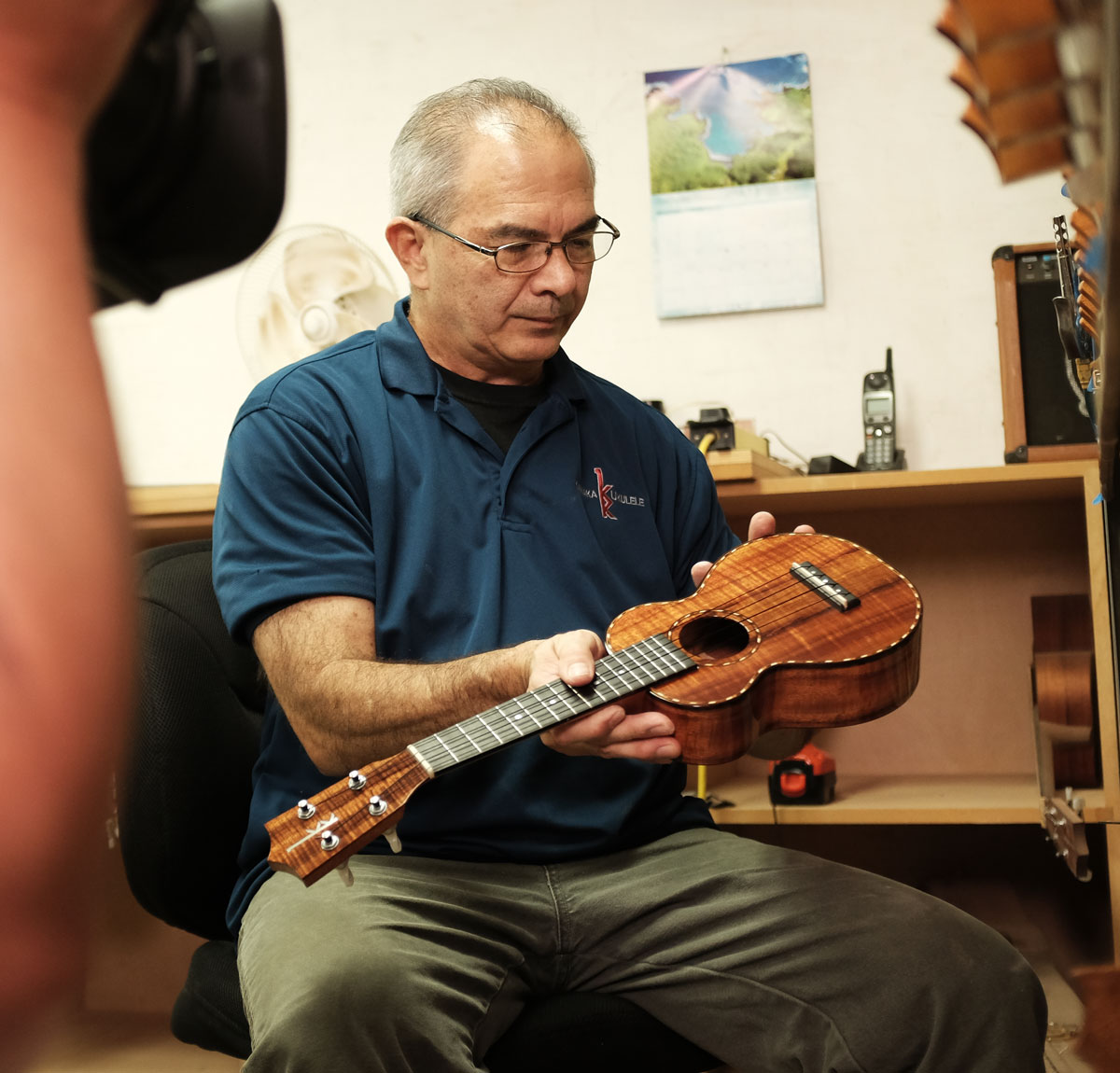 Chris inspects a ukulele while being filmed